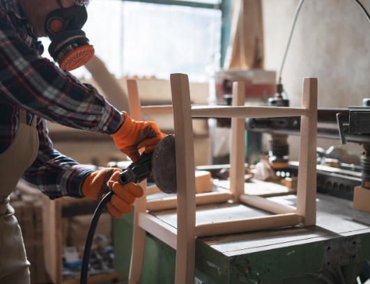 Lijado de un mueble en el taller de restauración Lijado de la estructura de un mueble de madera con lijadora orbital durante su restauración