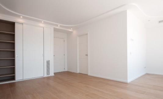 Reforma integral de madera en una vivienda de Málaga Dormitorio reformado en Málaga con armario empotrado corredero, puerta de paso lacada y suelo de madera nuevos